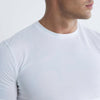 A close-up of a man wearing a plain white short-sleeve crew-neck t-shirt against a light gray background.